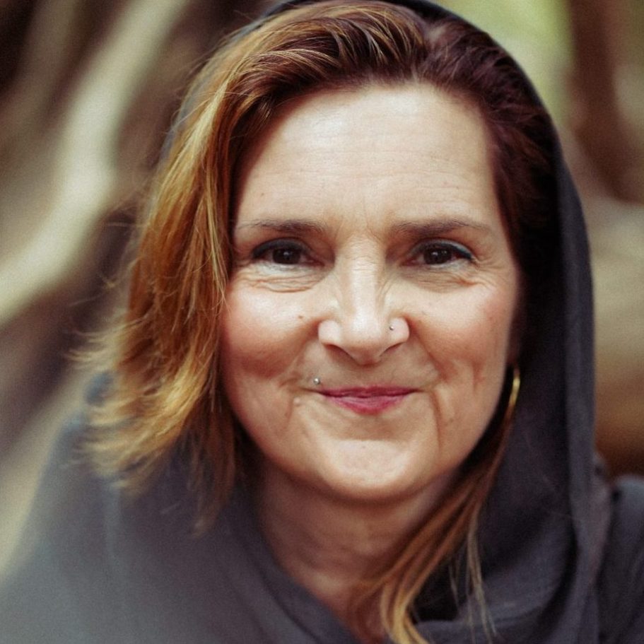 Portrait einer lächelnden Frau mit langen, braunen Haaren und dunklem Kopftuch.